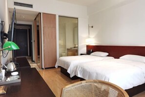 A hotel room with a bed, a desk with a lamp, a chair, and a mirror. - Yiwenge Hotel (Changshu)