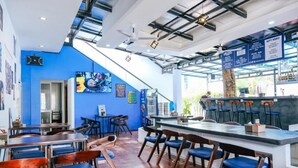 A restaurant with a blue interior, a bar area, and a staircase leading to an upper level. - Last Summer Hostel & Bar (Siem Reap)
