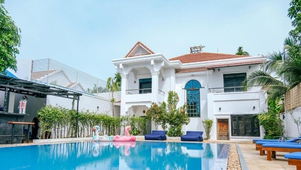A large swimming pool with lounge chairs and a pink flamingo float. - Last Summer Hostel & Bar (Siem Reap)