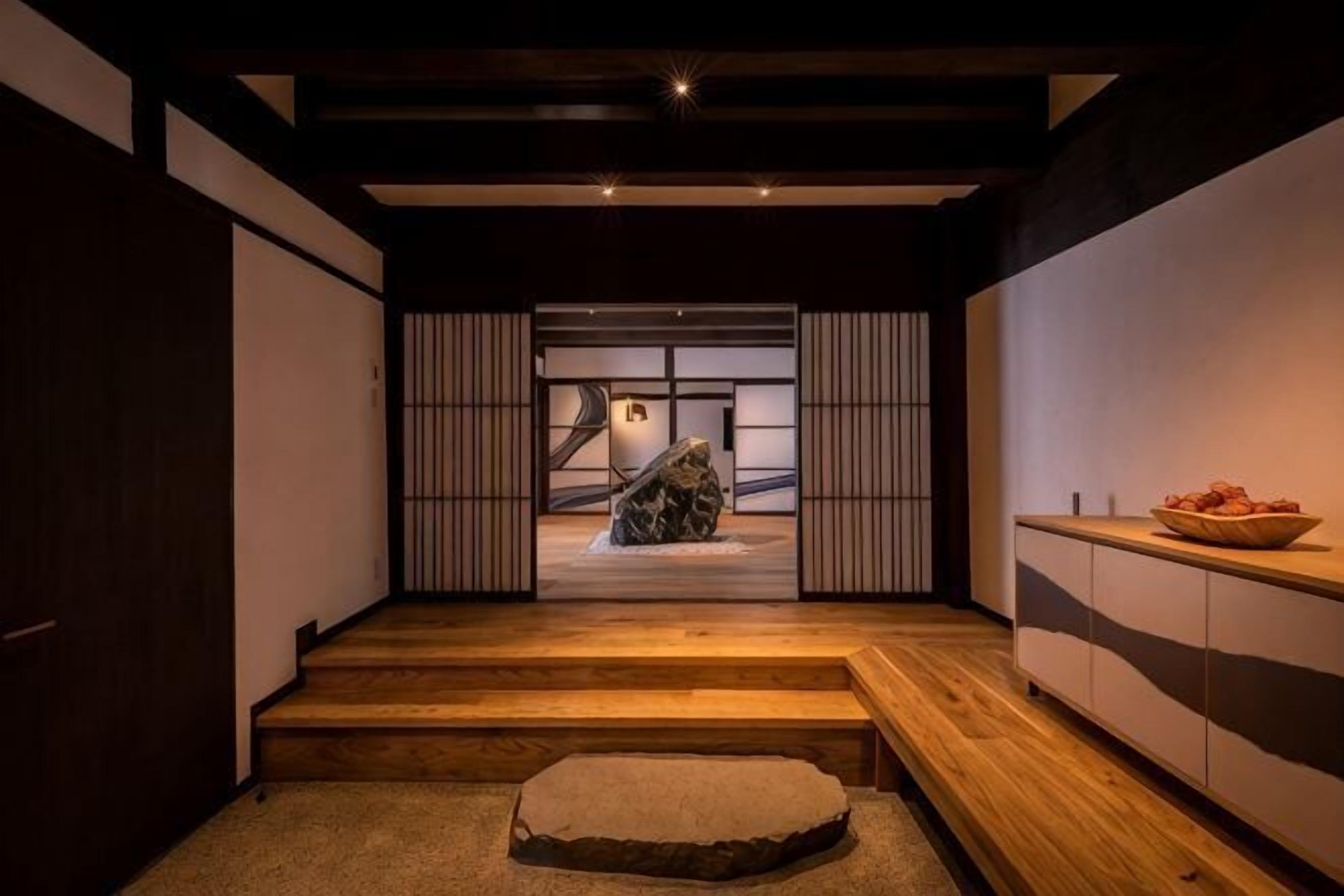 Een traditioneel Japans interieur met tatami vloeren, schuifdeuren en een houten bank.