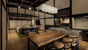 Cocina moderna con mesa y sillas de madera, una isla integrada con fregadero y una lámpara colgante grande.