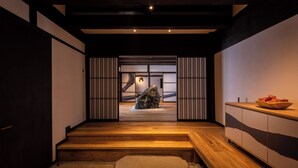 Un interior moderno con una escalera de madera, una escultura de piedra y un banco de madera.