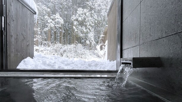 Un jacuzzi con vistas a un paisaje nevado a través de una puerta abierta.