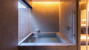 Un baño moderno con bañera empotrada, cabina de ducha de vidrio y un inodoro a la vista.