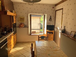Une cuisine avec des meubles de rangement en bois, une cuisinière et une fenêtre donnant sur l’extérieur.