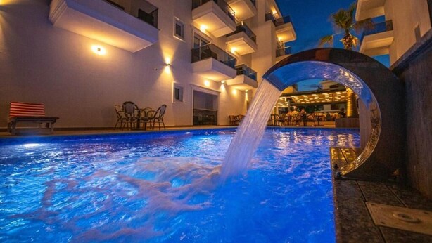 A hotel pool area with a water feature, outdoor seating, and a bar area visible through an archway. - L'Amo del Mare Hotel (Ksamil)
