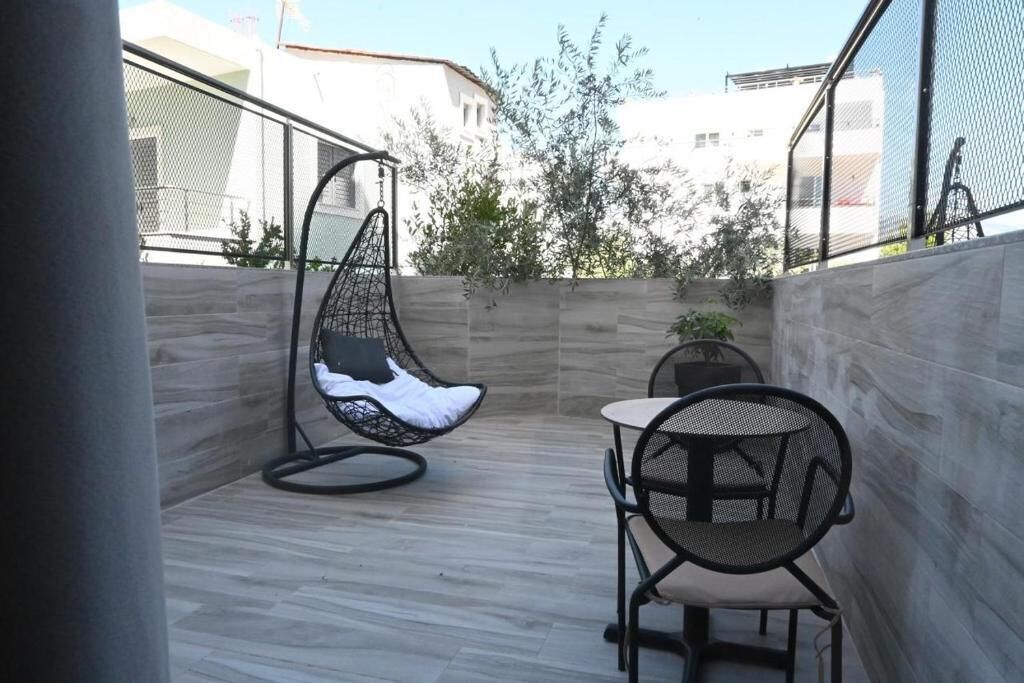 A small patio area with a hanging chair, a round table, and a potted plant.