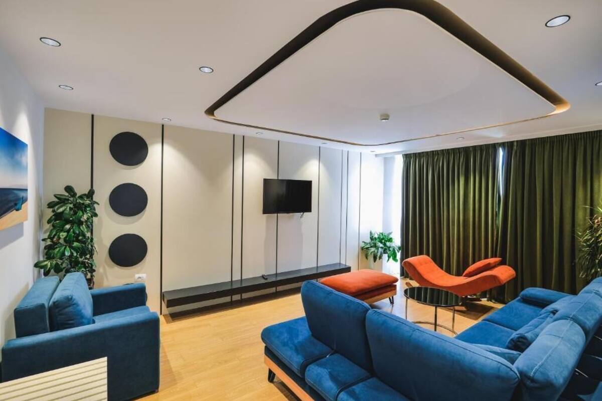 Una sala moderna con un sofá azul, un sillón rojo y un televisor de pantalla plana montado en la pared.