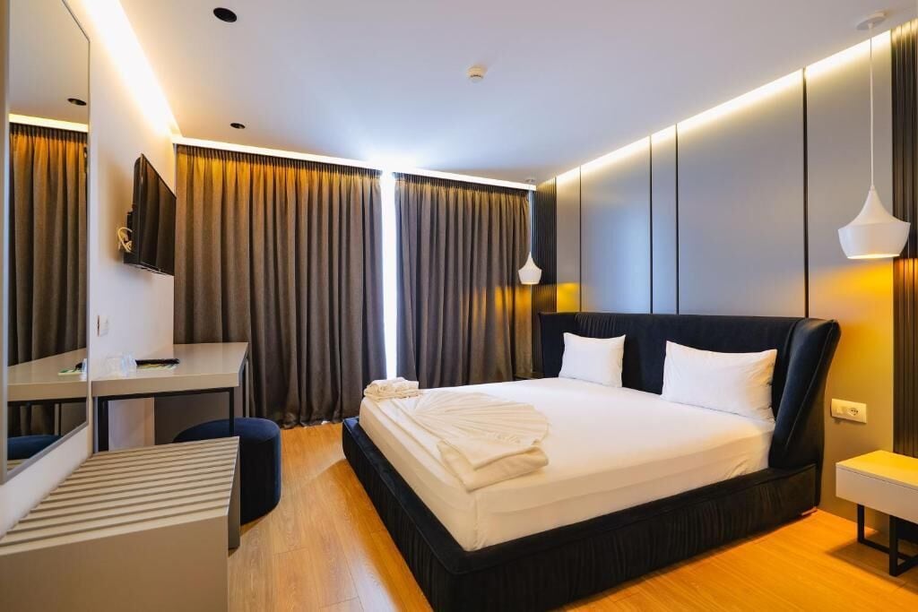 Una habitación de hotel moderna con una cama grande, un escritorio, una silla y un televisor.