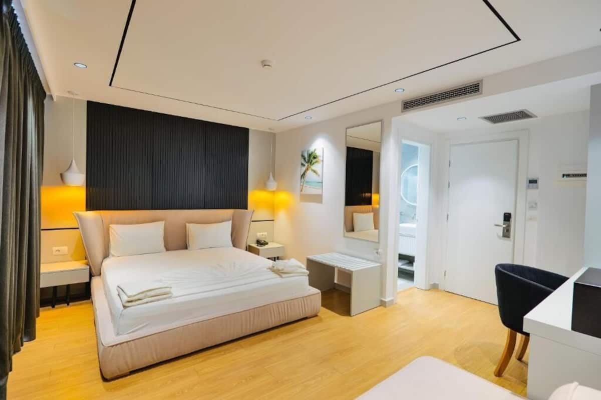 Una habitación de hotel moderna con una cama grande, mesitas de noche, un escritorio y una silla.