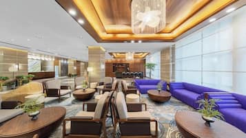 A spacious lobby with a seating area, a reception desk, and a large chandelier.