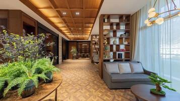 A modern interior with a wooden ceiling, a sofa, a table with plants, and a bookshelf.
