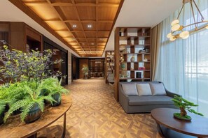 Een modern interieur met een houten plafond, een bank, een tafel met planten en een boekenplank.
