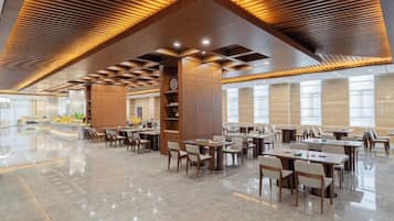 A spacious indoor area with multiple tables and chairs, a polished floor, and a wooden ceiling with recessed lighting.