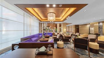 A spacious lobby with a wooden ceiling, a central seating area with sofas, and a large table.