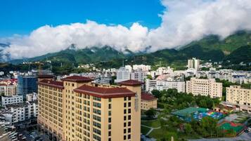 A cityscape with a prominent building, a mountainous backdrop, and a clear sky.