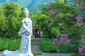 Eine Statue in einem Garten, im Hintergrund ein Gebäude.