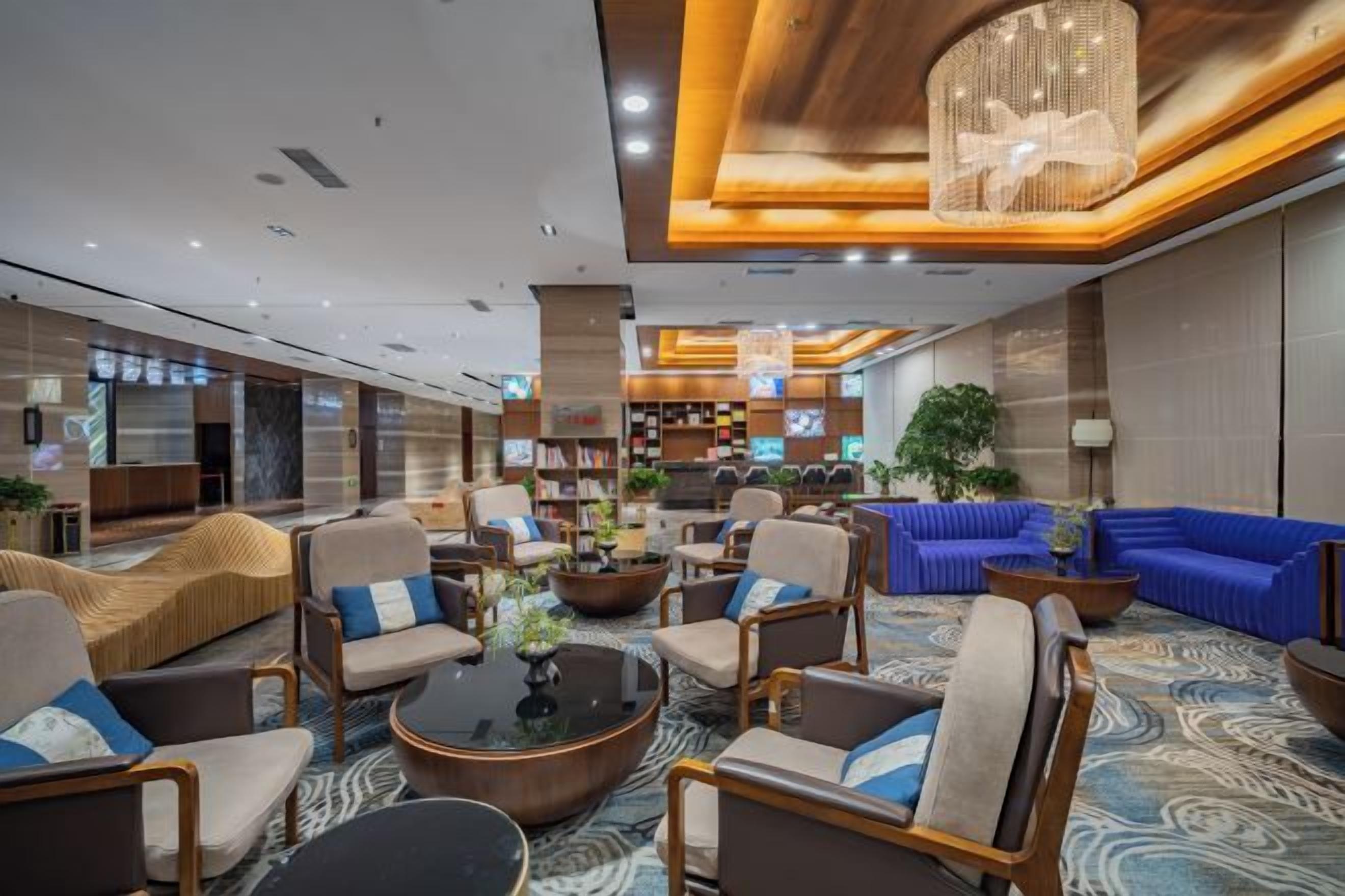 A modern lobby with seating areas, a coffee table, and a large chandelier.