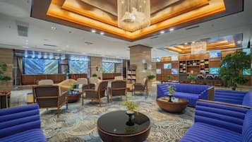 A hotel lobby with seating areas, a reception desk, and a large chandelier.
