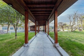 Un porticato con colonne che conduce a un edificio con vista su una zona erbosa e alberi.