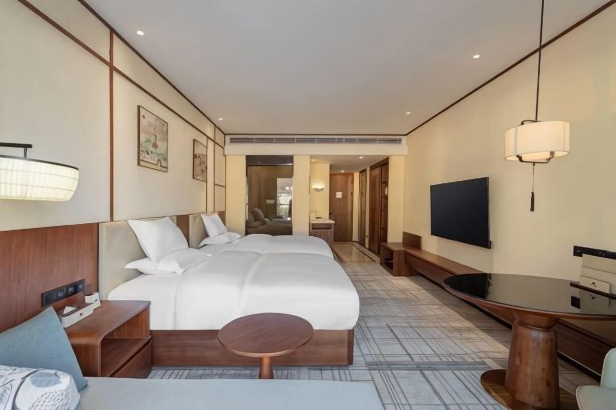 Ein Hotelzimmer mit einem großen Bett, einem Schreibtisch, einem Fernseher und einer Sitzecke.