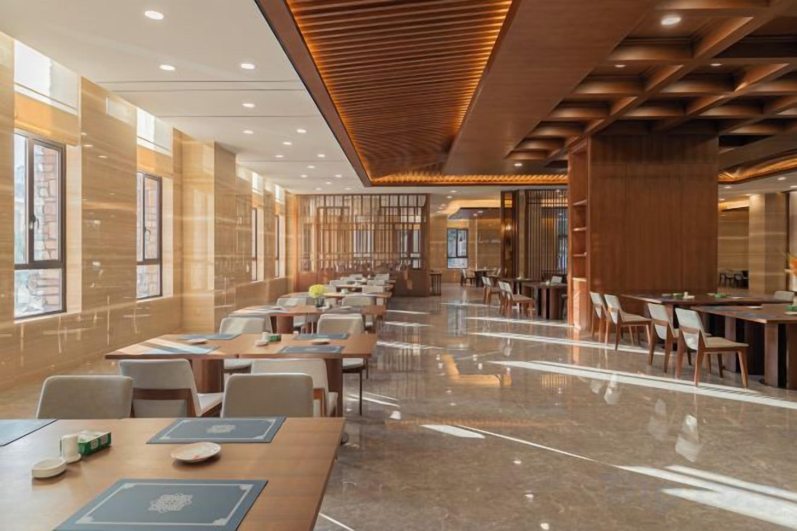 A spacious hotel lobby with multiple seating areas, a polished marble floor, and a modern ceiling design.