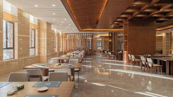 A spacious hotel lobby with multiple seating areas, a polished marble floor, and a modern ceiling design.
