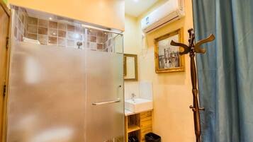 A bathroom with a glass shower enclosure, a sink, and a mirror.
