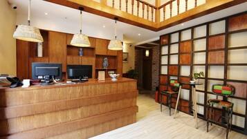 A reception area with a wooden counter, two televisions, and hanging lamps.