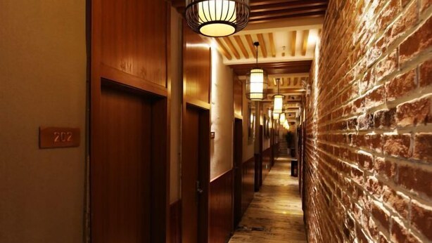 A hallway with wooden doors, a brick wall, and hanging lamps. - OYO Nanchang Happy Waterbed Literature Hotel (Nanchang)