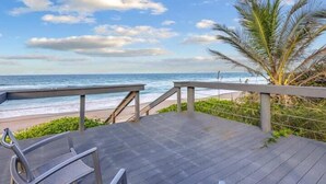 A wooden deck with a metal railing overlooking a beach. - Oceanfront Downstairs Duplex | 4BR + Beach Access (Melbourne Beach)