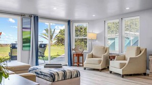Un salon spacieux doté d’une grande porte-fenêtre coulissante donnant sur un balcon, de deux fauteuils, d’un canapé et d’une petite table d’appoint.