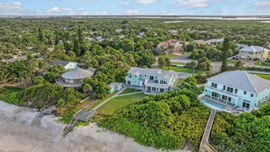 Un quartier résidentiel situé sur la côte, avec des maisons, une plage et une grande maison dotée d’une piscine.