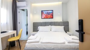 A modern hotel room with a bed, bedside tables, a desk, and a chair.