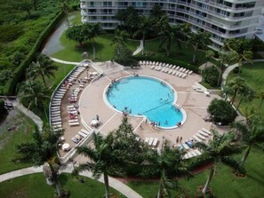 A hotel with a central pool surrounded by lounge chairs and palm trees. - Enjoy Glorious Sunset Views from the Balcony of this Beach Condo (Marco Island)