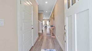 A hallway with a wooden floor, white doors, and a ceiling light fixture.