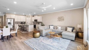 A modern living space with a kitchen, dining area, and a seating area with a sofa and coffee table.