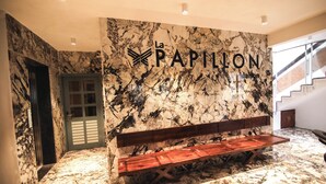 A marble lobby with a wooden bench, a door, and a staircase. - La Papillon Maison (Puducherry)