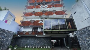 A multi-story building with a unique geometric facade, stone walls, and a glass entrance. - La Papillon Maison (Puducherry)