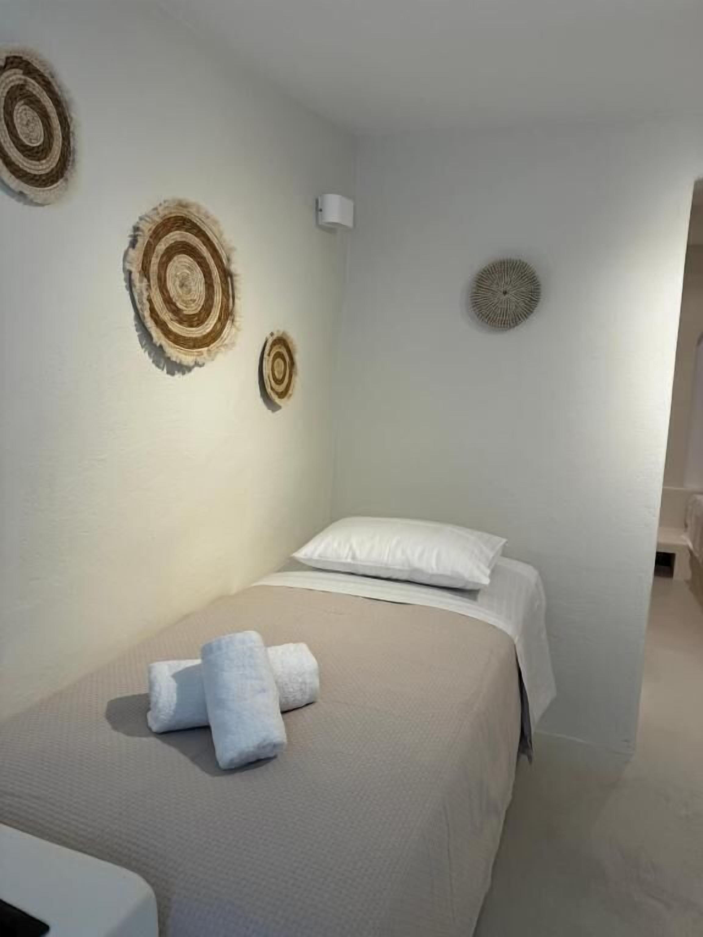 A bedroom with a bed, white pillows, and two wall-mounted circular wall art pieces.