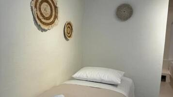 A bedroom with a bed, white pillows, and two wall-mounted circular wall art pieces.