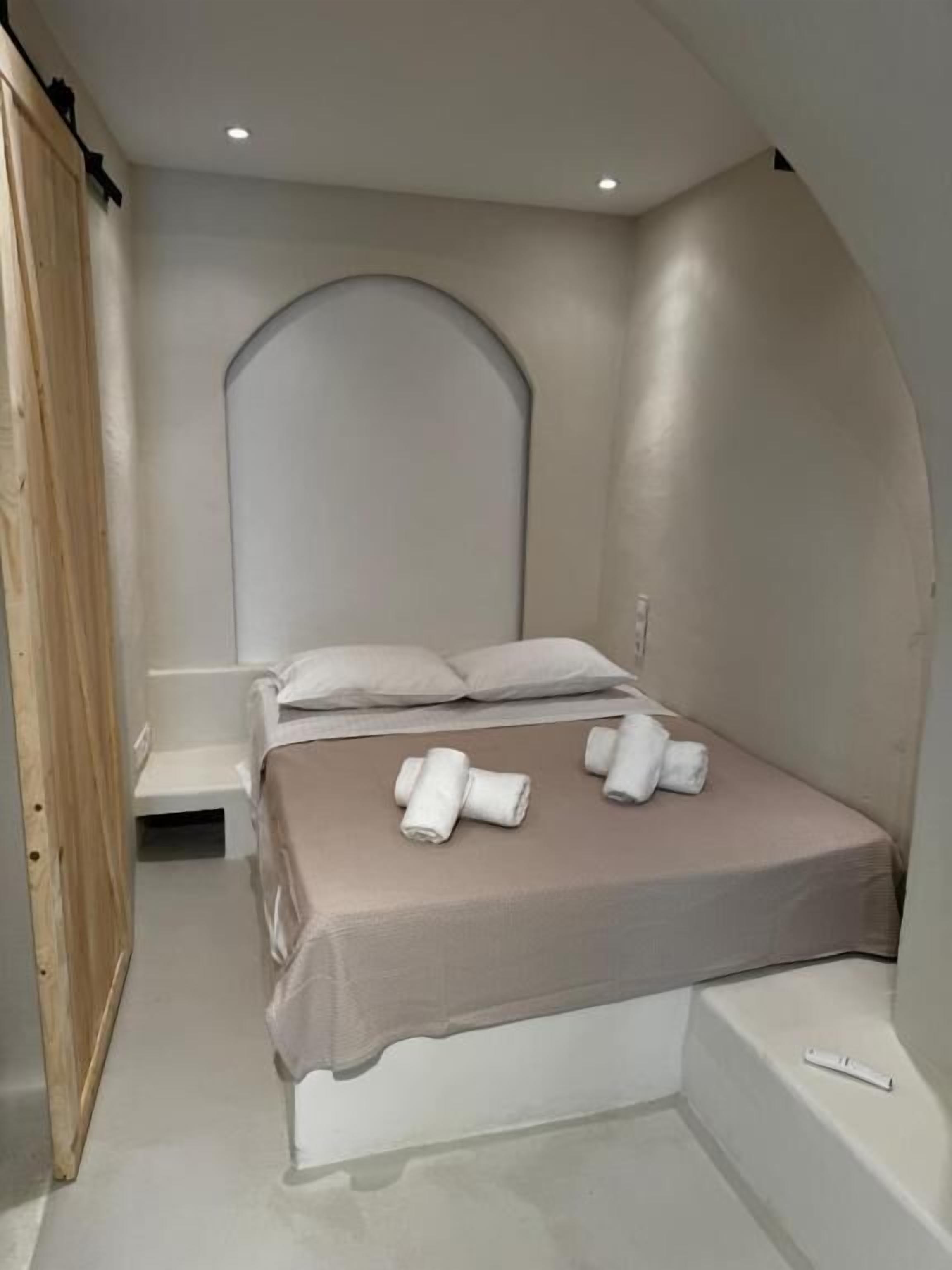 Quarto com cama, almofadas, um banco e toalhas.
