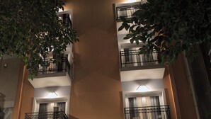 Un edificio de varios pisos con balcones, una tienda visible en la planta baja y un letrero que dice 'Allure Athens'.
