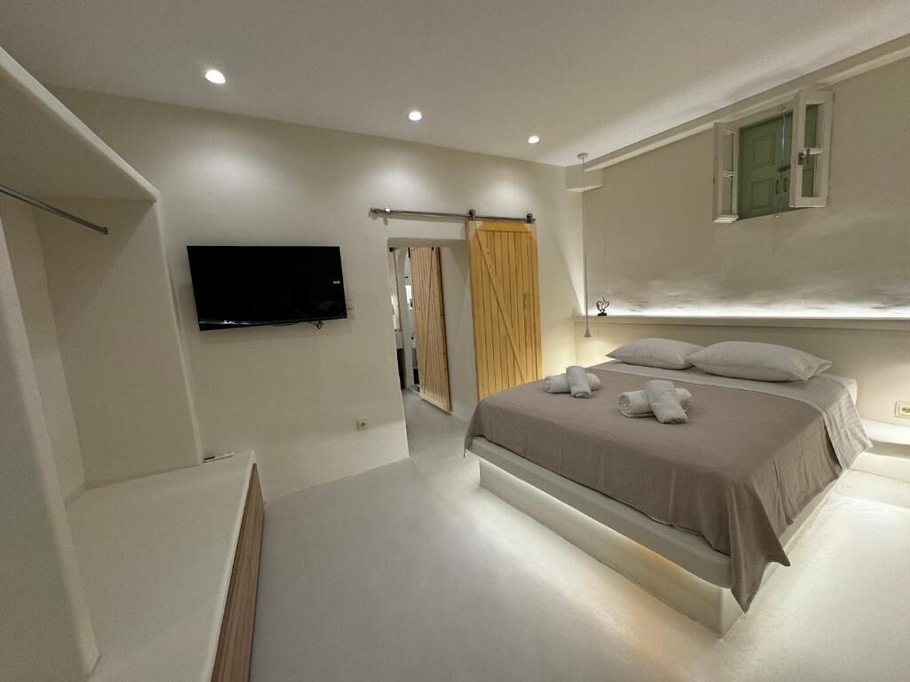 Un dormitorio moderno con una cama grande, un televisor de pantalla plana montado en la pared y un armario con puerta corredera.