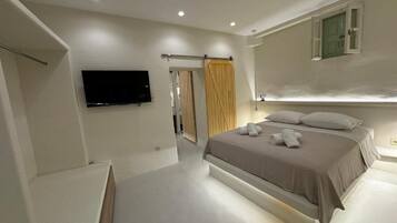 Un dormitorio moderno con una cama grande, un televisor de pantalla plana montado en la pared y un armario con puerta corredera.