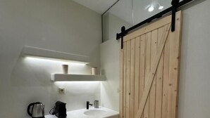 Un baño moderno con lavamanos, espejo y una puerta corredera de madera.
