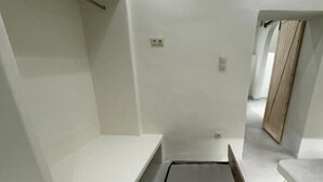 Habitación minimalista con cama, estanterías empotradas y una puerta de madera.