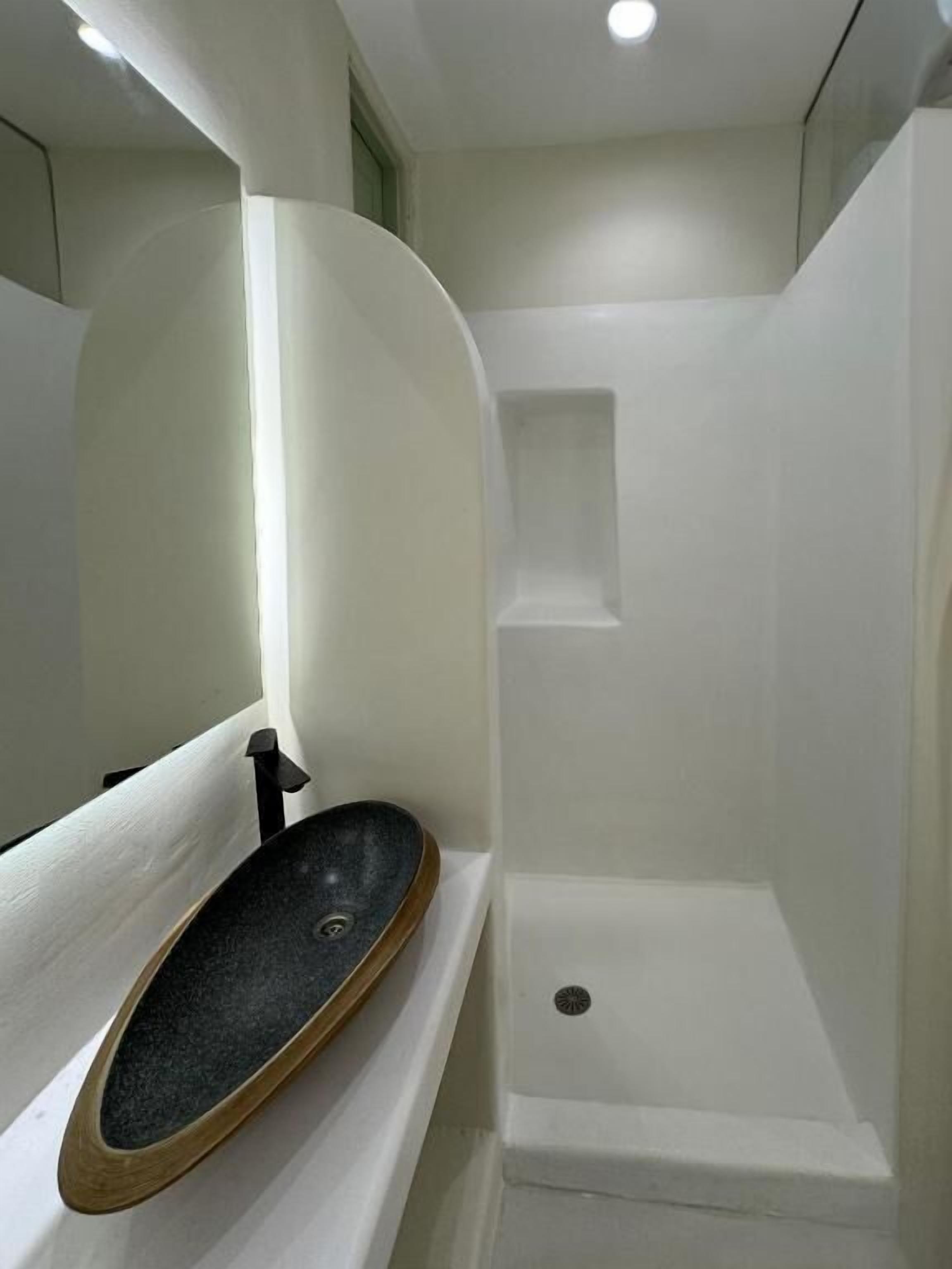 Un baño moderno con un lavamanos independiente, zona de ducha y un ventanal.