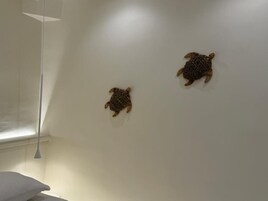 Una habitación con una pared blanca y dos adornos de pared con motivos de tortugas.