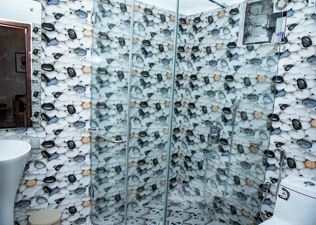 A shower with a mosaic wall design, a sink, and a toilet.